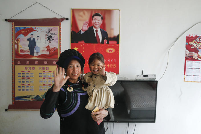 A minority woman and a child wave near posters showing images of Chinese President Xi Jinping and his wife Peng Liyuan on display on a wall at her house in Xujiashan village in Ganluo County, southwest China's Sichuan province on Sept. 10, 2020. Communist Party Xi’s smiling visage looks down from the walls of virtually every home inhabited by members of the Yi minority group in a remote corner of China’s Sichuan province. Xi has replaced former leader Mao Zedong for pride of place in new brick and concrete homes built to replace crumbling traditional structures in Sichuan’s Liangshan Yi Autonomous Prefecture, which his home to about 2 million members of the group. (AP Photo/Andy Wong)