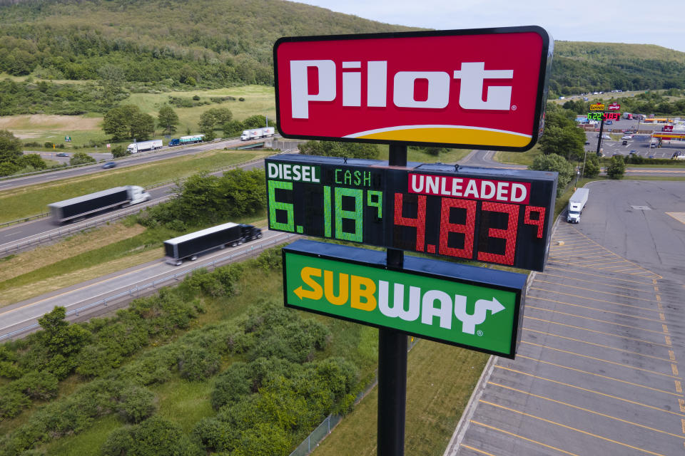 FILE - Trucks and cars drive by a Pilot Travel Center sign displaying fuel prices in Bath, New York, on Monday, June 20, 2022.