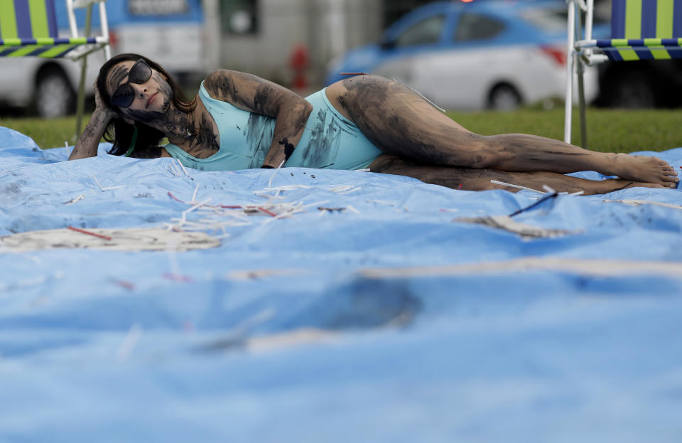 A demonstrator painted with fake oil lies on a tarp during a protest against the auction for the exploration of oil fields close to Abrolhos, a marine national park in Bahia state, in front of the Grand Hyatt Hotel where the auction is taking place, in Rio de Janeiro, Brazil, Thursday, Oct. 10, 2019. Under pressure from environmental organizations, none of the 17 companies involved in the process presented any offers. (AP Photo/Silvia Izquierdo)