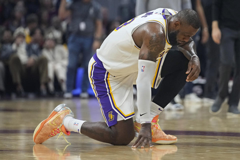 Los Angeles Lakers forward LeBron James kneels on the floor after being hurt during the first half of the team's NBA basketball game against the Cleveland Cavaliers, Saturday, Nov. 25, 2023, in Cleveland. (AP Photo/Sue Ogrocki)