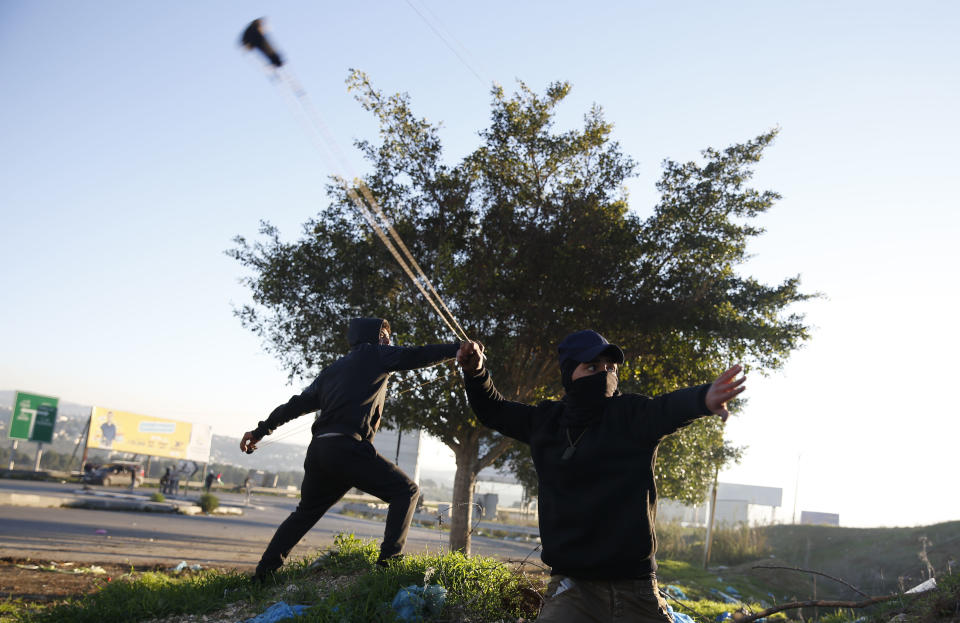 Palestinian protestor throws stones during clashes with Israeli troops at the Hawara checkpoint, south of the West Bank city of Nablus, Friday, Dec. 14, 2018. (AP Photo/Majdi Mohammed)