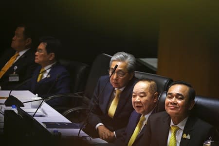 Thailand's Prime Minister Prayuth Chan-ocha smiles as he sits next to his members of cabinet before delivering the policy statement of the council of ministers to the parliament, at the parliament in Bangkok