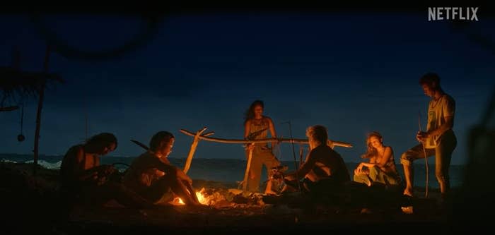 The entire group sat near a fire on the beach