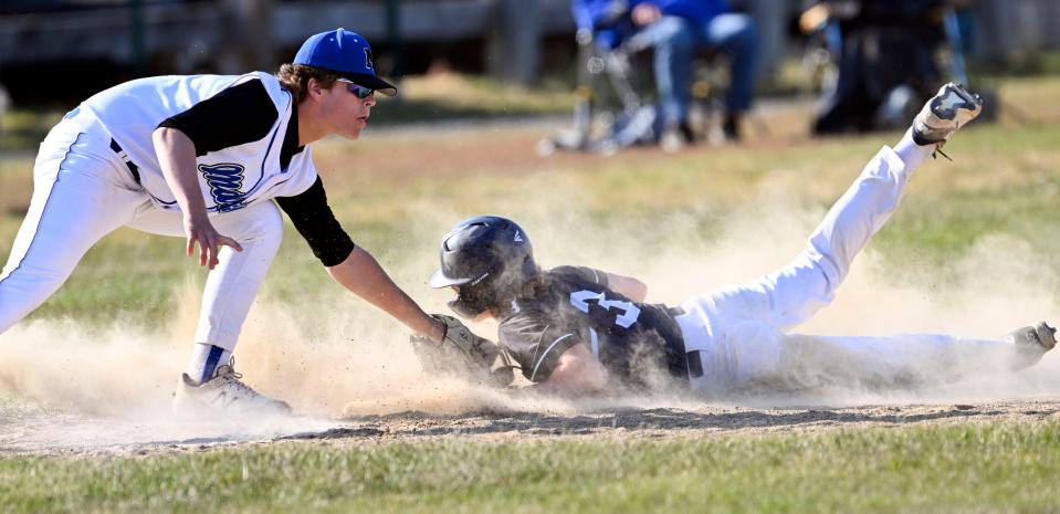 Chace Robbins of Monomoy slides under the tag of Mashpee third baseman James Brady.