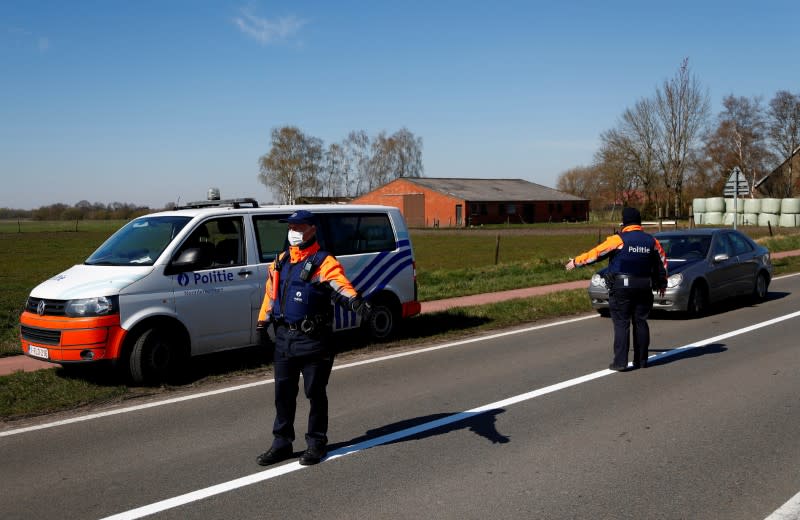 FILE PHOTO: Belgian police officers wearing a protective mask gesture to drivers on the Belgian-Dutch border in Meersel-Dreef