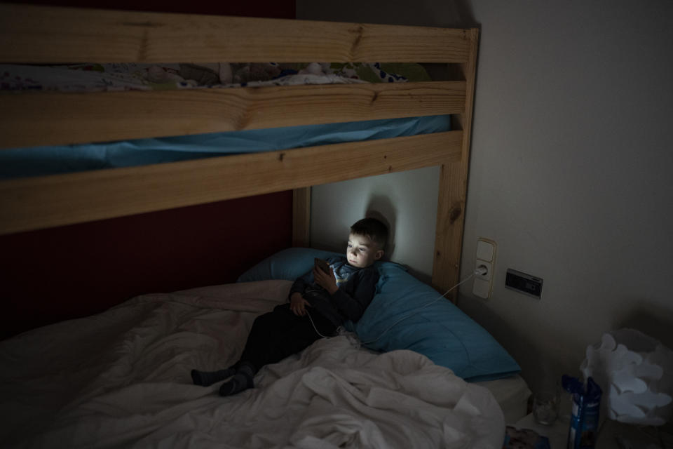 FILE - Maxym Batrak, 5, from Brovary, looks at a phone in a house in the village of Guissona, Lleida, Spain, on March 22, 2022. The U.N. refugee agency says more than 4 million refugees have now fled Ukraine following Russia’s invasion, a new milestone in the largest refugee crisis in Europe since World War II. (AP Photo/Joan Mateu Parra).