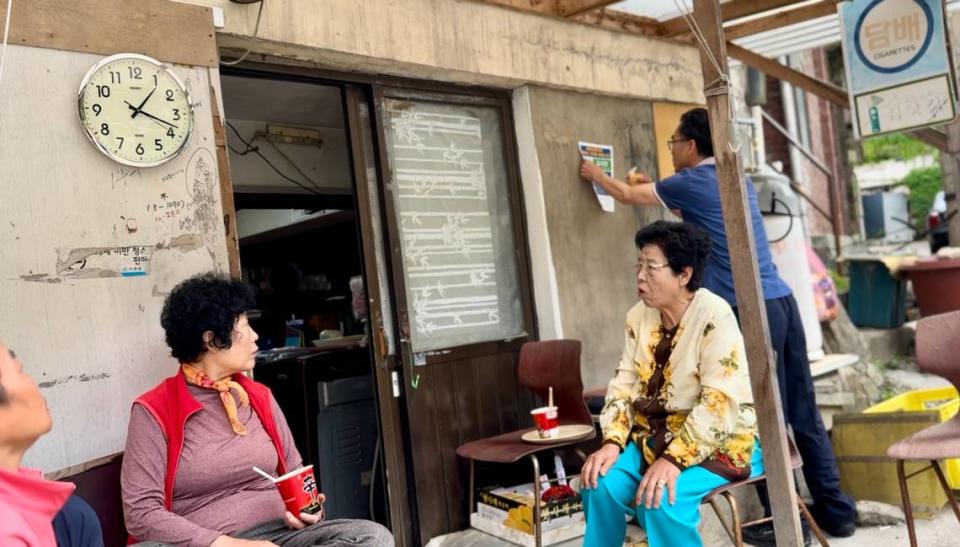 A local government employee hangs Théoden Janes’s flyer in an old section of Hyeonjeo-dong, which is the area of Seoul where he was purported to be found as an abandoned infant.