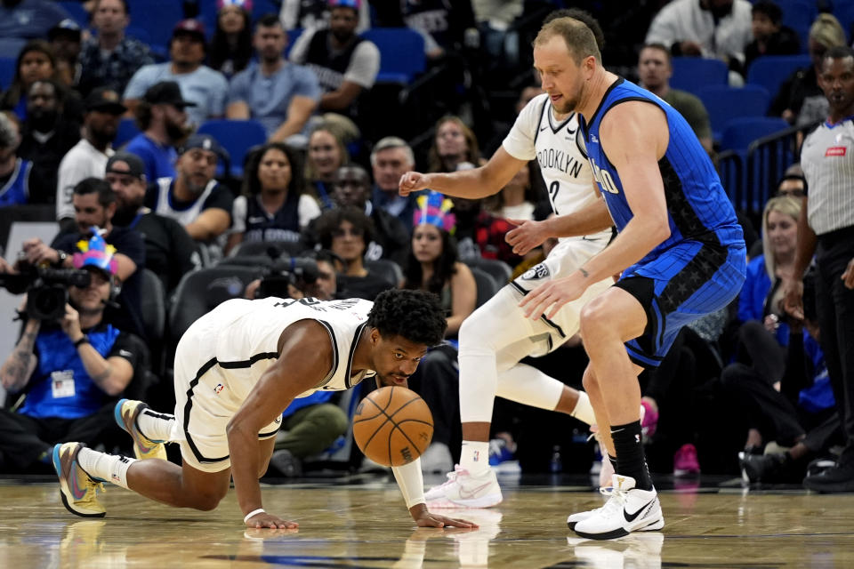 Brooklyn Nets guard Dennis Smith Jr., left, and forward Cameron Johnson, center, go after a loose ball against Orlando Magic guard Joe Ingles, right, during the first half of an NBA basketball game, Tuesday, Feb. 27, 2024, in Orlando, Fla. (AP Photo/John Raoux)