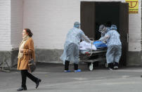 FILE - In this Thursday, Oct. 21, 2021 file photo, medical staff members carry a cart with dead body out of the COVID-19 infection department in a city clinic in Kyiv, Ukraine. Ukraine is suffering through a surge in coronavirus infections, along with other parts of Eastern Europe and Russia. While vaccines are plentiful, there is a widespread reluctance to get them in many countries — though notable exceptions include the Baltic nations, Poland, the Czech Republic, Slovenia and Hungary. (AP Photo/Efrem Lukatsky, File)