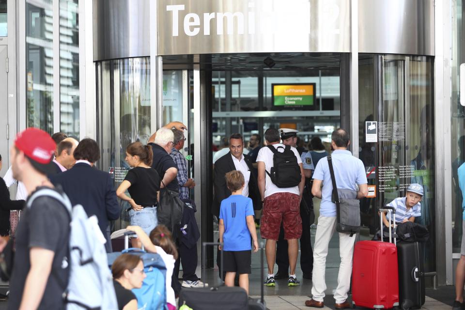 People wait outside the Munich Airport in Munich, Germany, Tuesday, Aug. 27, 2019, after some of its terminals were closed because a person has likely entered the "clean area" through an emergency exit door. The international airport tweeted Tuesday morning that terminal 2 and areas B and C of terminal 1 had been closed for police operations.(AP Photo/Matthias Schrader)