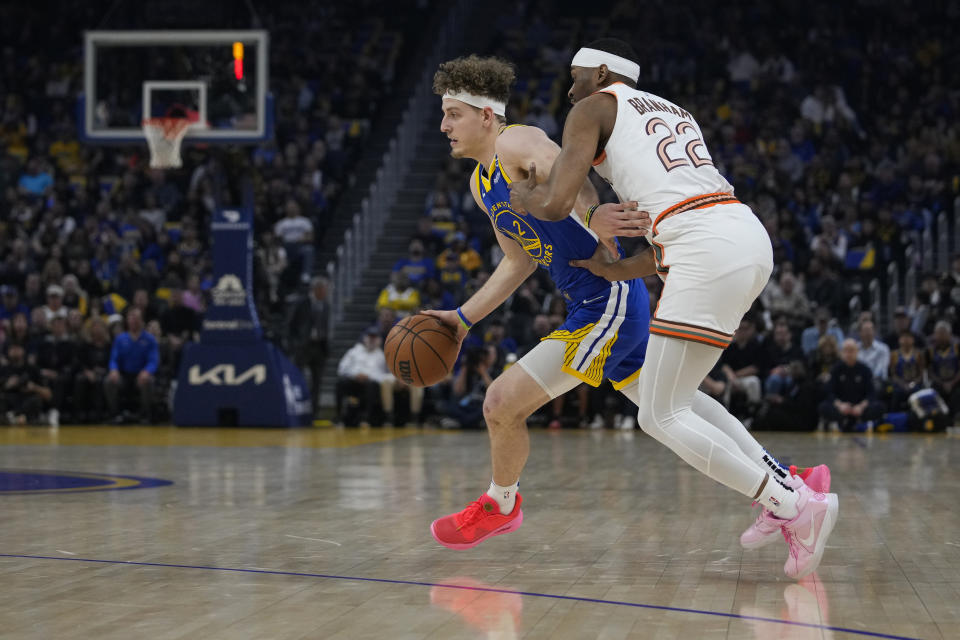 Golden State Warriors guard Brandin Podziemski (2) moves the ball while defended by San Antonio Spurs guard Malaki Branham during the first half of an NBA basketball game Saturday, March 9, 2024, in San Francisco. (AP Photo/Godofredo A. Vásquez)