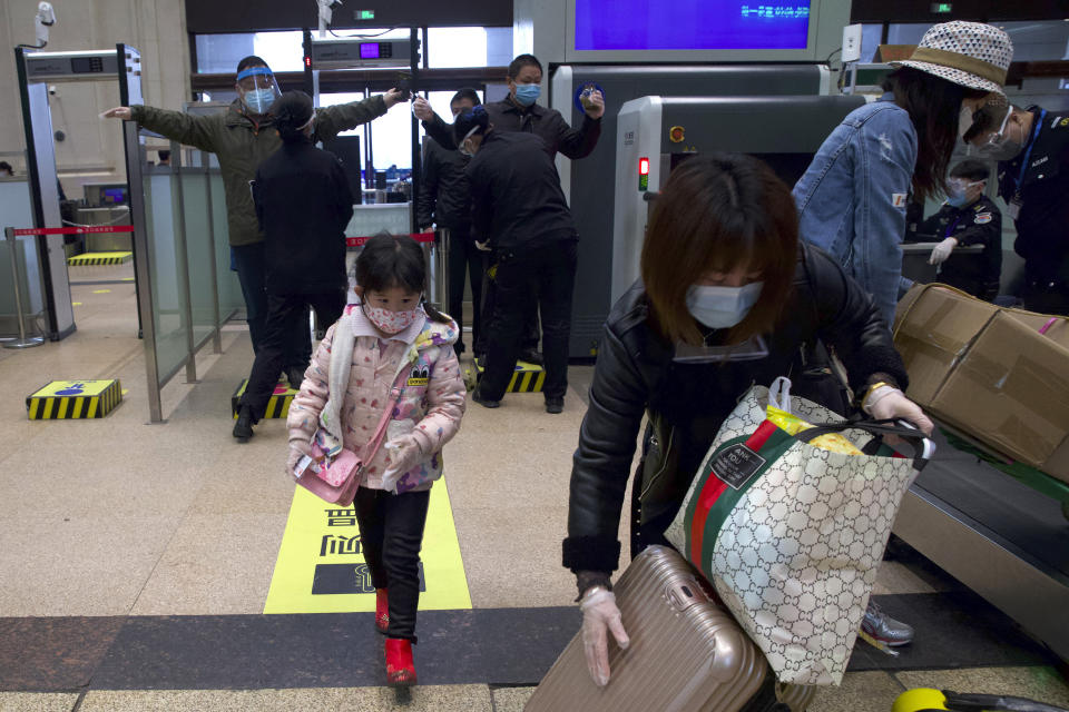 Passengers wearing face masks to protect against the spread of coronavirus pass through security checks at Hankou train station after the resumption of train services in Wuhan.