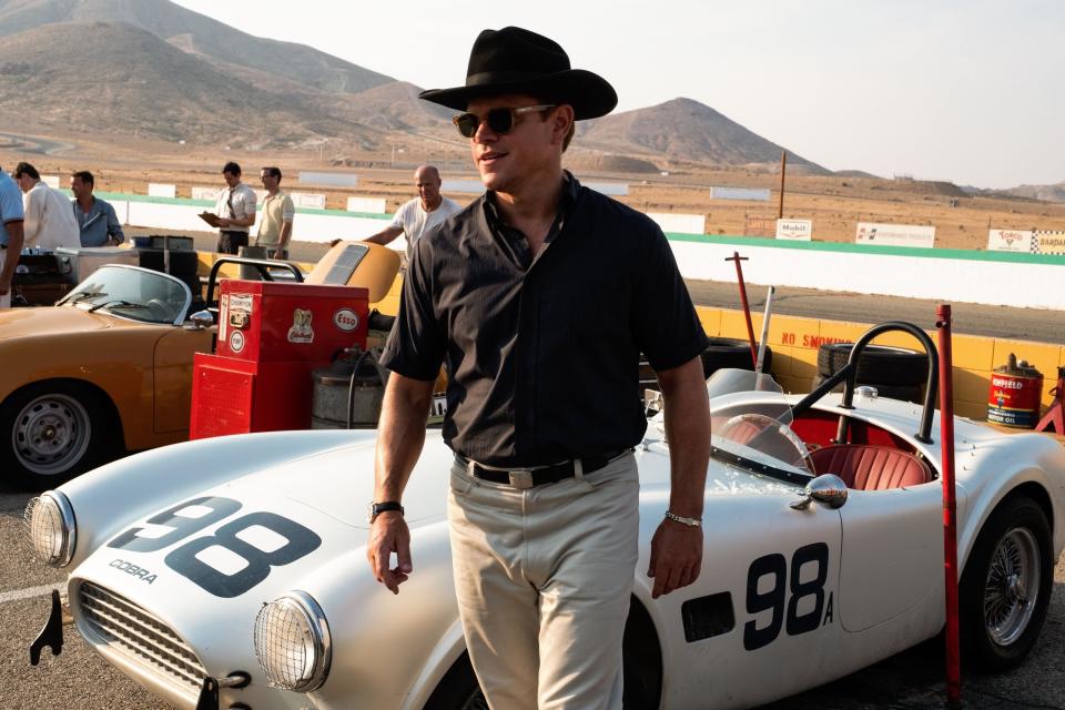 Matt Damon walks past a vintage race car