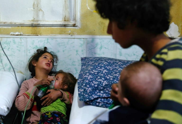 A Syrian girl holds an oxygen mask over the face of an infant following a reported gas attack on the rebel-held town of Douma in the Eastern Ghouta region