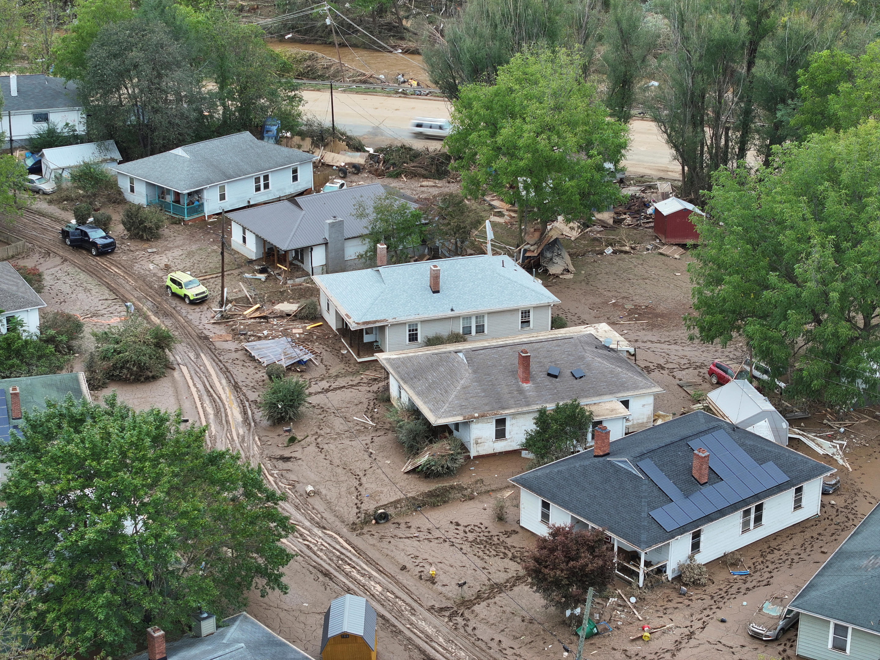 Homes in a damaged area surrounded by mud and debris.