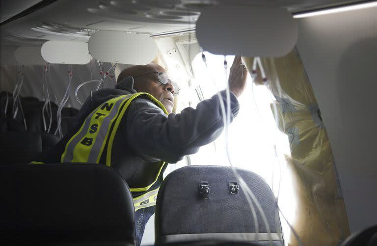 En esta foto publicada por la Junta Nacional de Seguridad del Transporte (NTSB), el Investigador a Cargo de la NTSB, John Lovell, examina la zona del enchufe del fuselaje del vuelo 1282 de Alaska Airlines el domingo 7 de enero de 2024, en Portland, Oregon. 