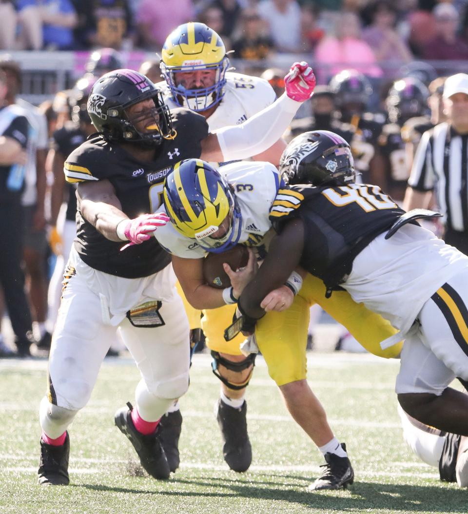 Delaware quarterback Zach Marker (3) is tackled by Towson's Jesus Gibbs (left) and Dion Crews-Harris late in the fourth quarter at Johnny Unitas Stadium in Towson, Md., Saturday, Oct. 28, 2023.