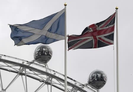 The British Union Flag (R) and a Scottish Saltire flag fly above the Scottish Office in Whitehall, with the London Eye wheel seen behind, in London, Britain, March 14, 2017. Brexit may not be a game-changer in the debate about Scottish independence, according to research published on March 30, 2017 that suggests Scots want similar outcomes as other Britons do from the United Kingdom's exit from the European Union. REUTERS/Toby Melville/Files