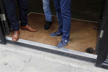 Men stand in the doorway of a barbers shop, which has a burn mark on the carpet in London September 3, 2013. REUTERS/Stefan Wermuth
