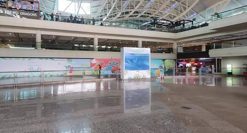 An empty Bali airport is seen in this photo with only a few people seen on a balcony.