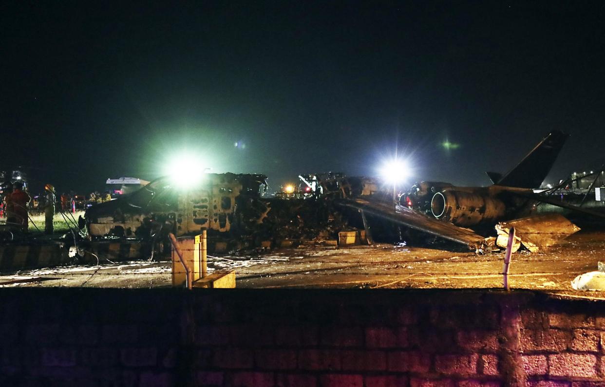 Firemen and rescuers stand beside the remains of a Lion Air, West Wind 24 aircraft after it caught fire during take off at Manila's International Airport in Philippines: AP