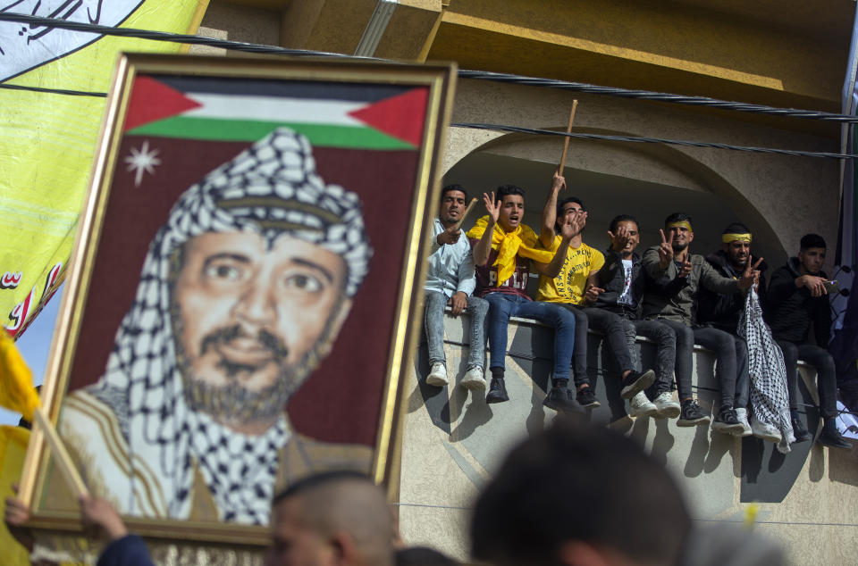 A man carries a picture of the late Palestinian leader, Yasser Arafat, during a rally marking the 55th anniversary of the Fatah movement founding, a secular Palestinian party and former guerrilla movement founded by Arafat, in Gaza City, Wednesday, Jan. 1, 2020. (AP Photo/Khalil Hamra)