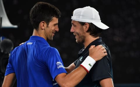 Novak Djokovic (L) speaks with France's Lucas Pouille after winning their men's singles semi-final match on day 12 of the Australian Open tennis tournament in Melbourne on January 25, 2019 - Credit: AFP