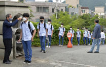 Students wearing face masks to help protect against the spread of the new coronavirus stand in a line to have their body temperatures checked before entering their classrooms at a high school in Ulsan, South Korea, Wednesday, Jun 3, 2020. (Bae Byung-soo/Newsis via AP)