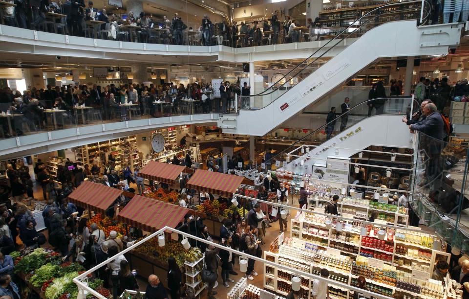 People gather during the opening day of upmarket Italian food hall chain Eataly's flagship store in downtown Milan, March 18, 2014. Eataly, which began with the idea that there should be a place to buy, eat and study high-quality Italian food and wine, has 25 food emporiums in the United States, Turkey, Japan and Dubai. REUTERS/Alessandro Garofalo (ITALY - Tags: SOCIETY FOOD BUSINESS)