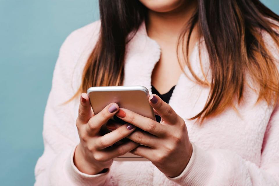 teen girl texting on smartphone wearing pink jacket