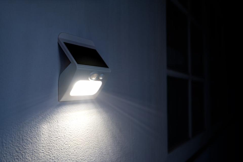 A close up of an outdoor motion sensor light shining at night. 