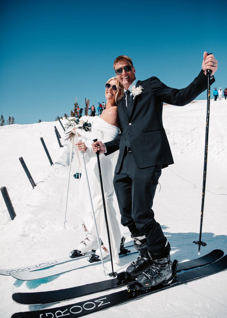 A bride and groom lean together while they're on skis.