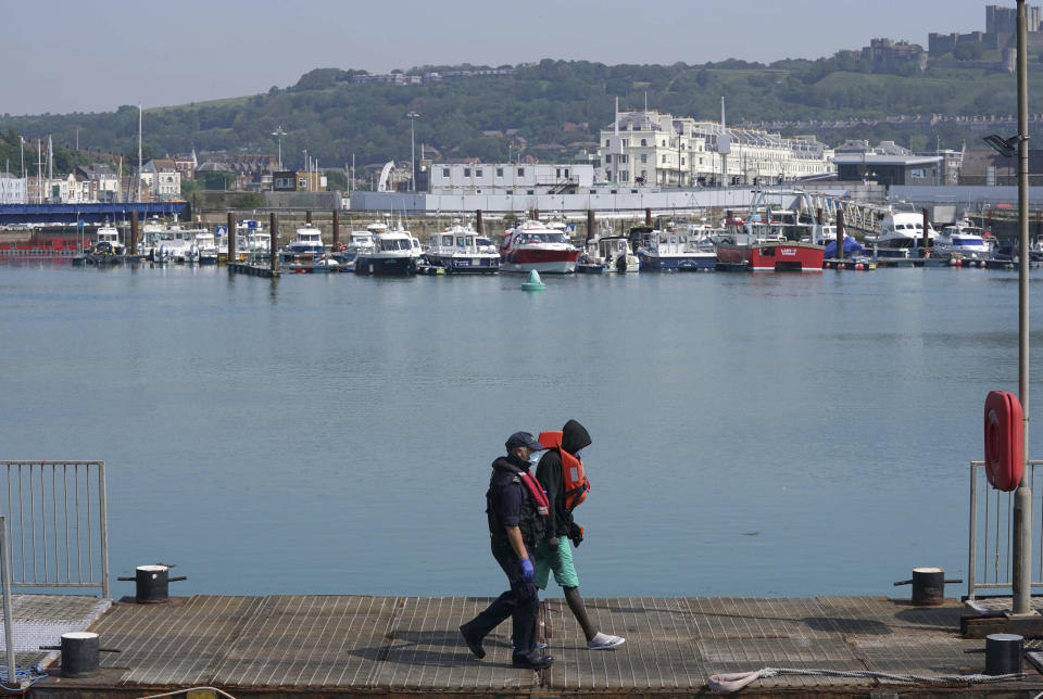 CORRECTING DATE - A man thought to be a migrant is escorted after disembarking from a border force boat following a small boat incident in the Channel, at Dover, southern England, Wednesday July 21, 2021. According to information released Tuesday, the number of undocumented migrants reaching Britain in small boats this year has surpassed the total for all of 2020, as people smugglers take advantage of good weather to cross the English Channel from France. (Gareth Fuller/PA via AP)