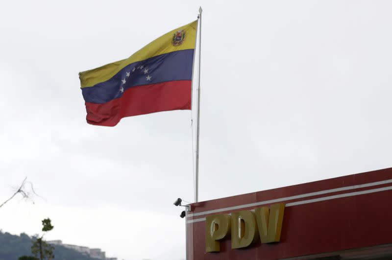 The logo of a subsidiary of the Venezuelan state oil company PDVSA is seen next to Venezuela's flag at a gas station in Caracas