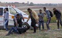 Medics and protesters run to evacuate a wounded youth from near the fence of the Gaza Strip border with Israel during a protest east of Gaza City, Friday, Nov. 16, 2018. (AP Photo/Adel Hana)