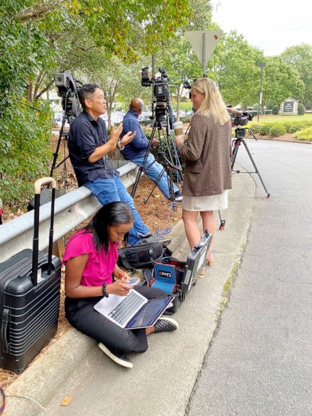 PHOTO: Embedded ABC News campaign reporter Lalee Ibssa (seated) works while covering Herschel Walker outside First Baptist Church Atlanta. (ABC News)