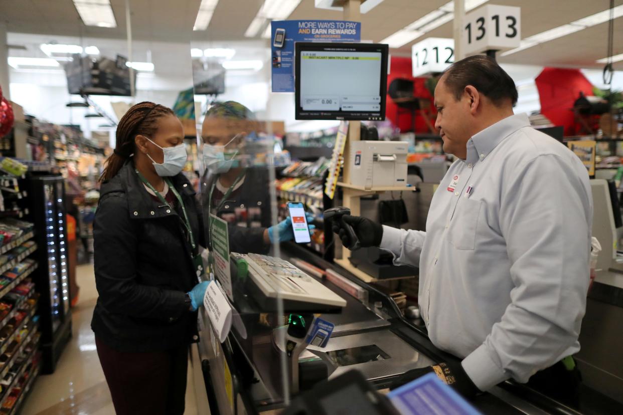 Assistant store manager Jesus Alvarez rings up groceries from behind a new plexiglass barrier at Ralphs Kroger grocery store after California issued a stay-at-home order in an effort to prevent the spread of coronavirus disease (COVID-19), in Los Angeles, California, U.S., March 30, 2020.  REUTERS/Lucy Nicholson