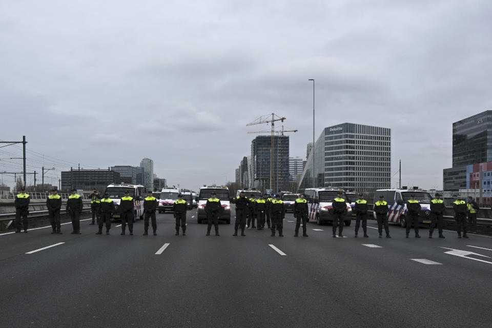 Police officers face climate activists blocking the main highway around Amsterdam near the former headquarters of a ING bank to protest its financing of fossil fuels, Saturday, Dec. 30, 2023. Protestors walked onto the road at midday, snarling traffic around the Dutch capital in the latest road blockade organized by the Dutch branch of Extinction Rebellion. (AP Photo/Patrick Post)