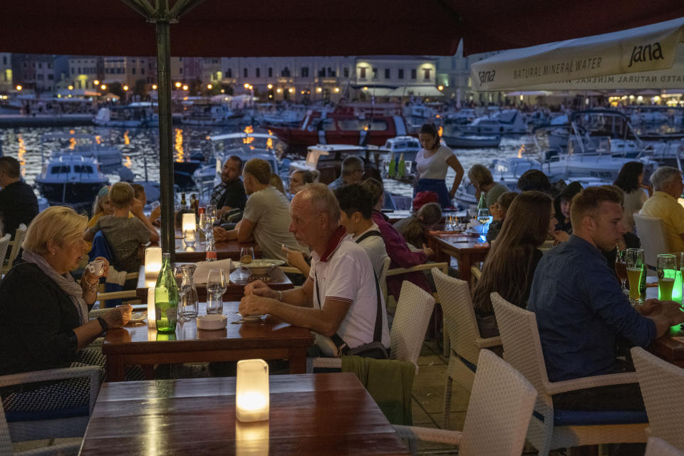 Holidaymakers sit in a seafront restaurant, in the Adriatic town of Rovinj, Croatia, Friday, Aug. 27, 2021. Summer tourism has exceeded even the most optimistic expectations in Croatia this year. Beaches along the country's Adriatic Sea coastline are swarming with people. Guided tours are fully booked, restaurants are packed and sailboats were chartered well in advance. (AP Photo/Darko Bandic)