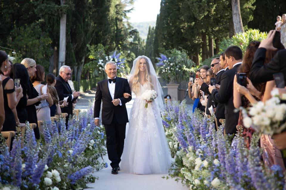 Caroline walking down the aisle escorted by her father.
