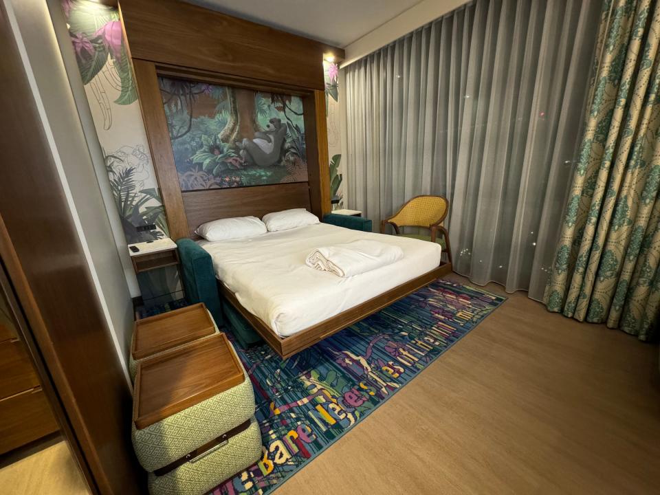 Bed with pillows, blankets in front of Jungle Bed mural in Disneyland Hotel duo studio room