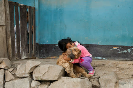 Crystel Acevedo plays with her dog outside her home in Nueva Union shantytown in Villa Maria del Triunfo district of Lima, Peru, May 9, 2018. REUTERS/Mariana Bazo