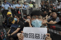 Protesters gather behind police line calling Hong Kong Chief Executive Carrie Lam to step down as they continue protest against the unpopular extradition bill near the Legislative Council in Hong Kong, Monday, June 17, 2019. A member of Hong Kong's Executive Council says the city's leader plans to apologize again over her handling of a highly unpopular extradition bill. (AP Photo/Kin Cheung)