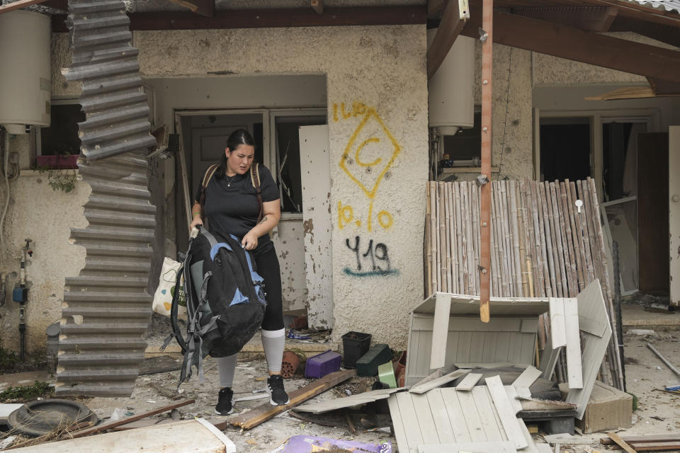 A woman recovers items from a house damaged during the Hamas attack in Kibbutz Kfar Azza, Israel, Friday, Oct. 27, 2023. The Kibbutz was attacked on Oct. 7. (AP Photo/Maya Alleruzzo)