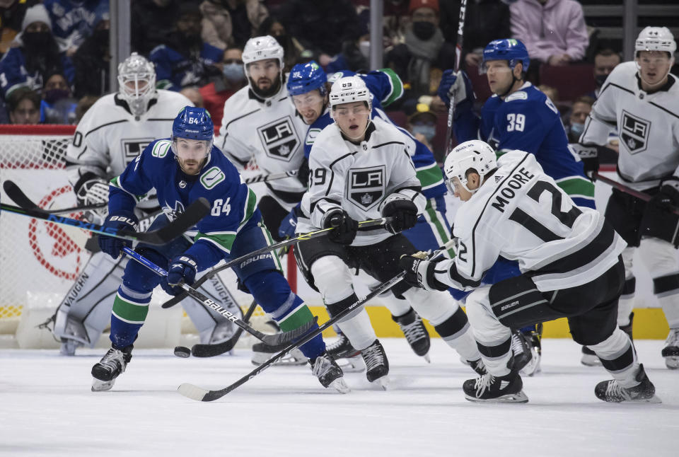 Vancouver Canucks' Tyler Motte (64) vies for the puck against Los Angeles Kings' Rasmus Kupari (89), of Finland, and Trevor Moore (12) during first-period NHL hockey game action in Vancouver, British Columbia, Monday, Dec. 6, 2021. Darryl Dyck/The Canadian Press via AP)