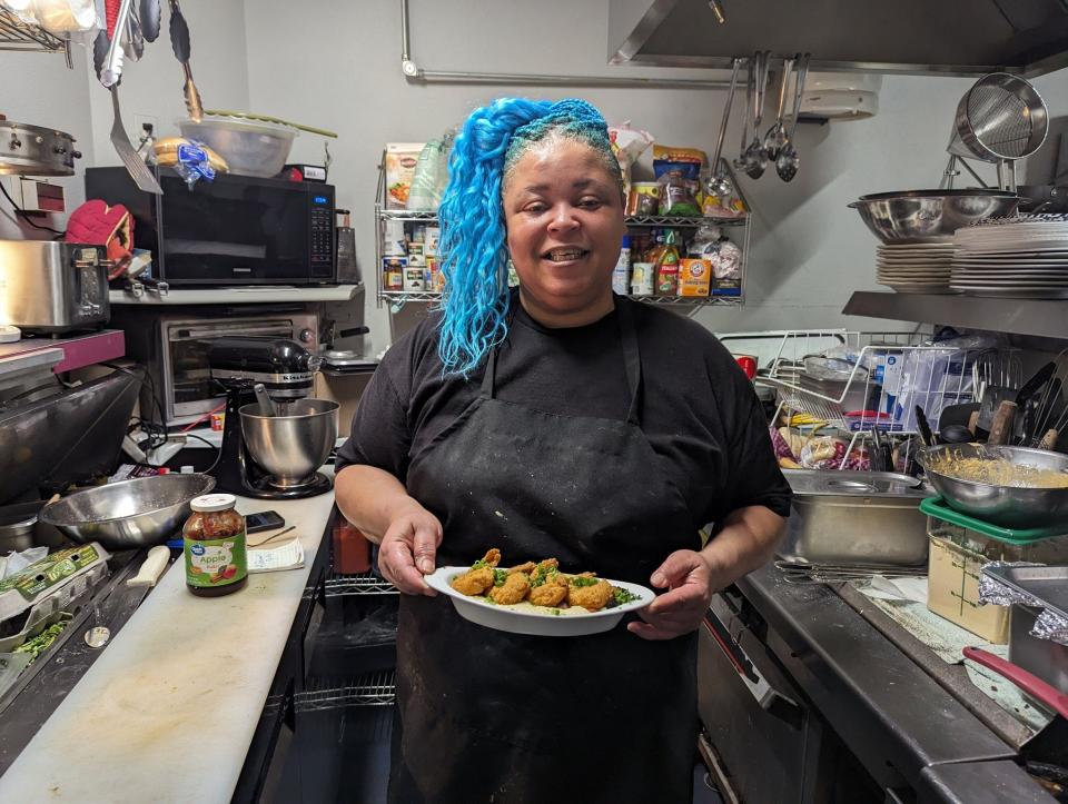 Riegna Breaux with a plate of shrimp and grits from her breakfast pop-up inside The Dehn Bar.