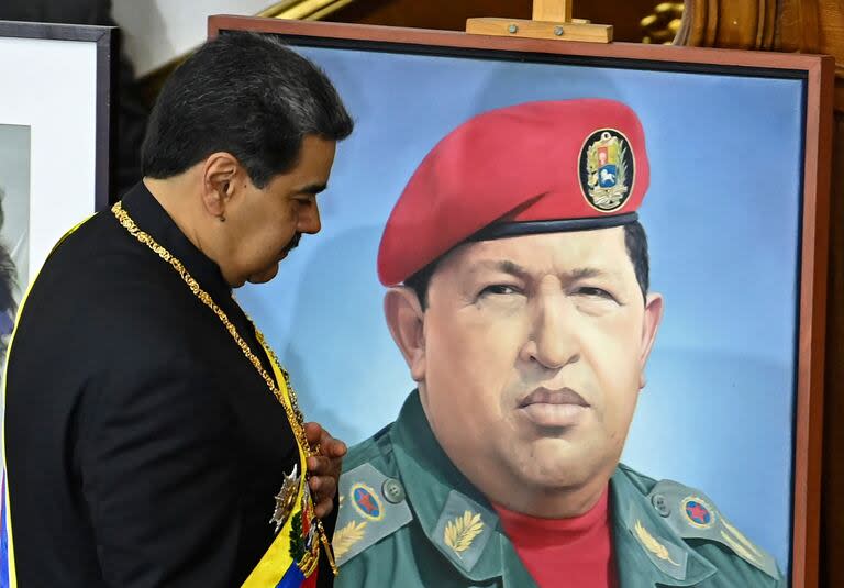 En esta foto de archivo tomada el 12 de enero de 2023, el presidente venezolano Nicolás Maduro pasa junto a un retrato del fallecido presidente Hugo Chávez