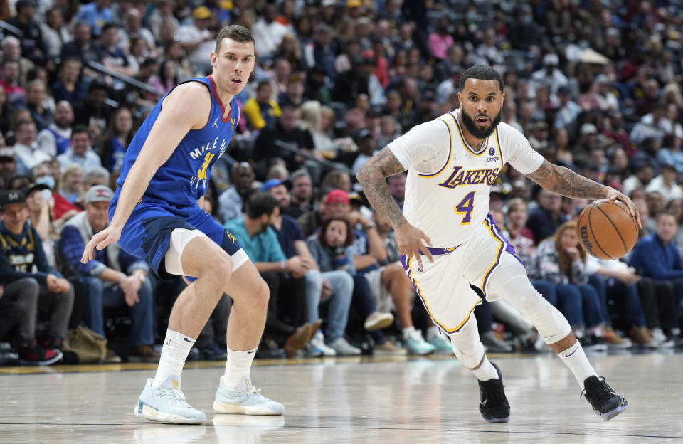 Los Angeles Lakers guard D.J. Augustin, right, drives past Denver Nuggets forward Vlatko Cancar in the first half of an basketball game Sunday, April 10, 2022, in Denver. (AP Photo/David Zalubowski)