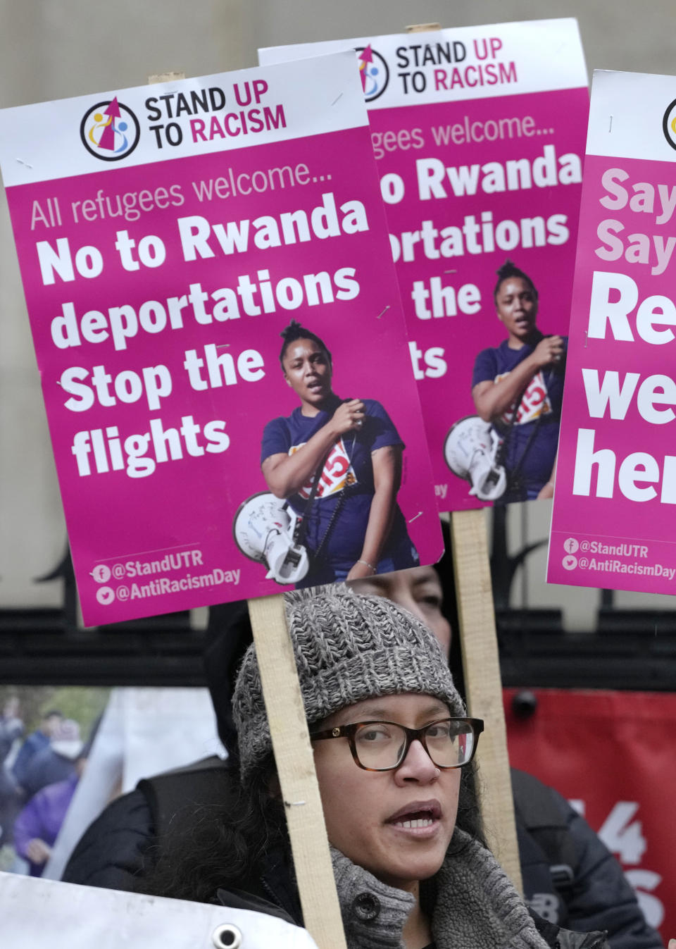 Stand Up To Racism campaigners hold banners outside the High Court in London, Monday, Dec. 19, 2022. Judges at Britain’s High Court say the U.K. government’s controversial plan to send asylum-seekers on a one-way trip to Rwanda is legal. But two judges also ruled that the government failed to consider the circumstances of the individuals it tried to deport. (AP Photo/Kirsty Wigglesworth)