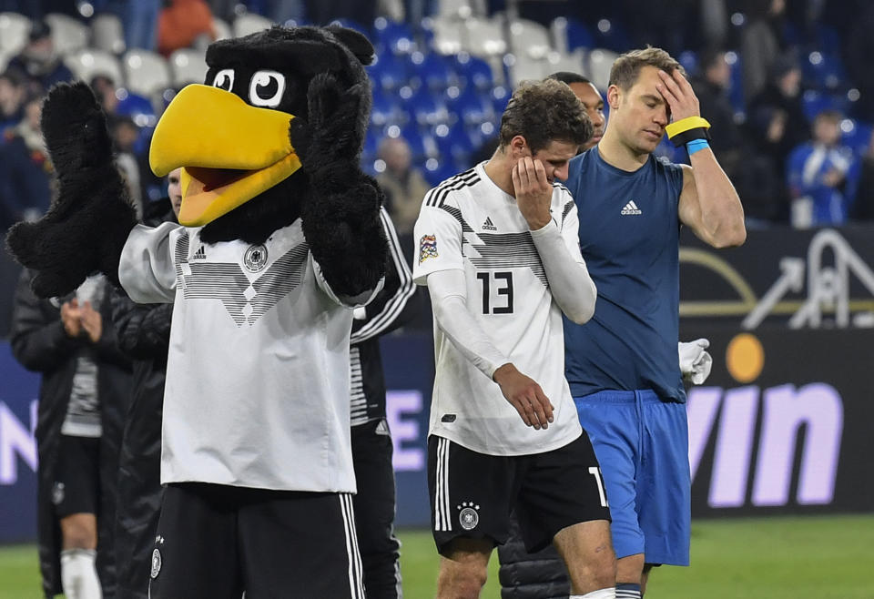 Germany's keeper Manuel Neuer and Thomas Mueller leave the pitch beside the mascot disappointed after the UEFA Nations League soccer match between Germany and The Netherlands in Gelsenkirchen, Monday, Nov. 19, 2018. The match ended 2-2, with two Dutch goals in the last 5 minutes. Germany have been relegated from League A of the Nations League. (AP Photo/Martin Meissner)